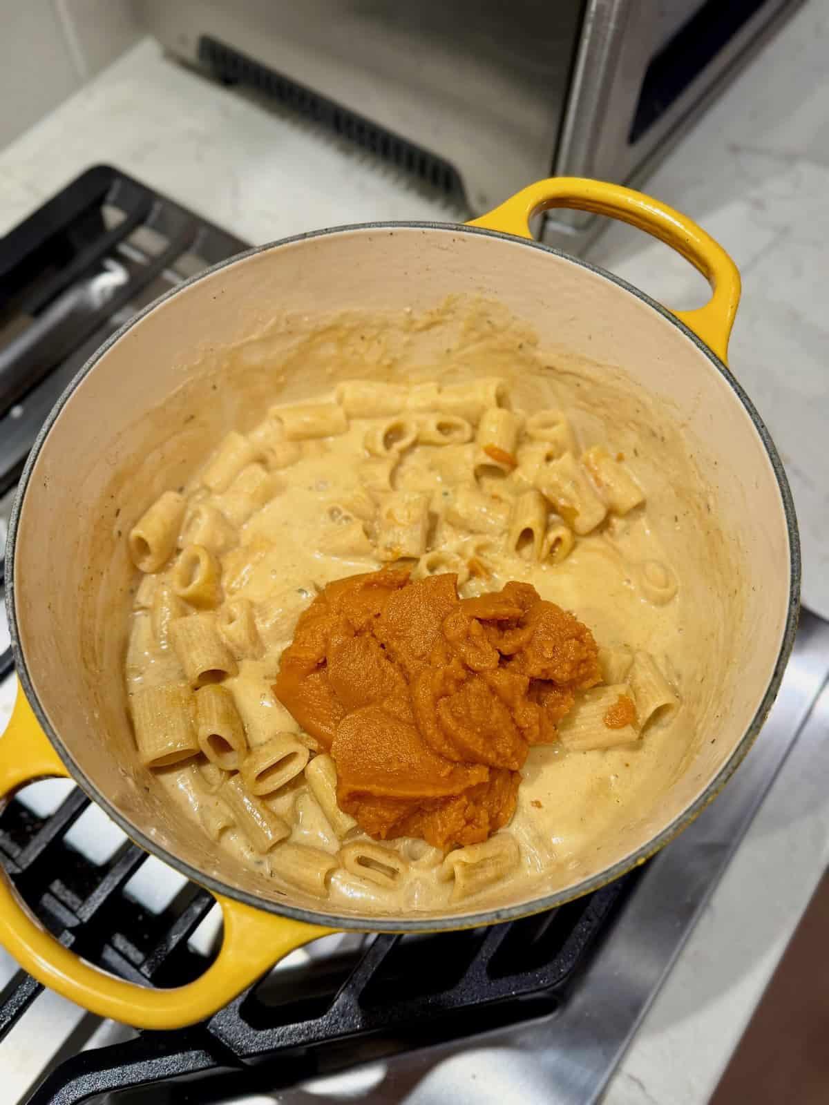 Pumpkin purée is added to the partially cooked pasta and creamy sauce.