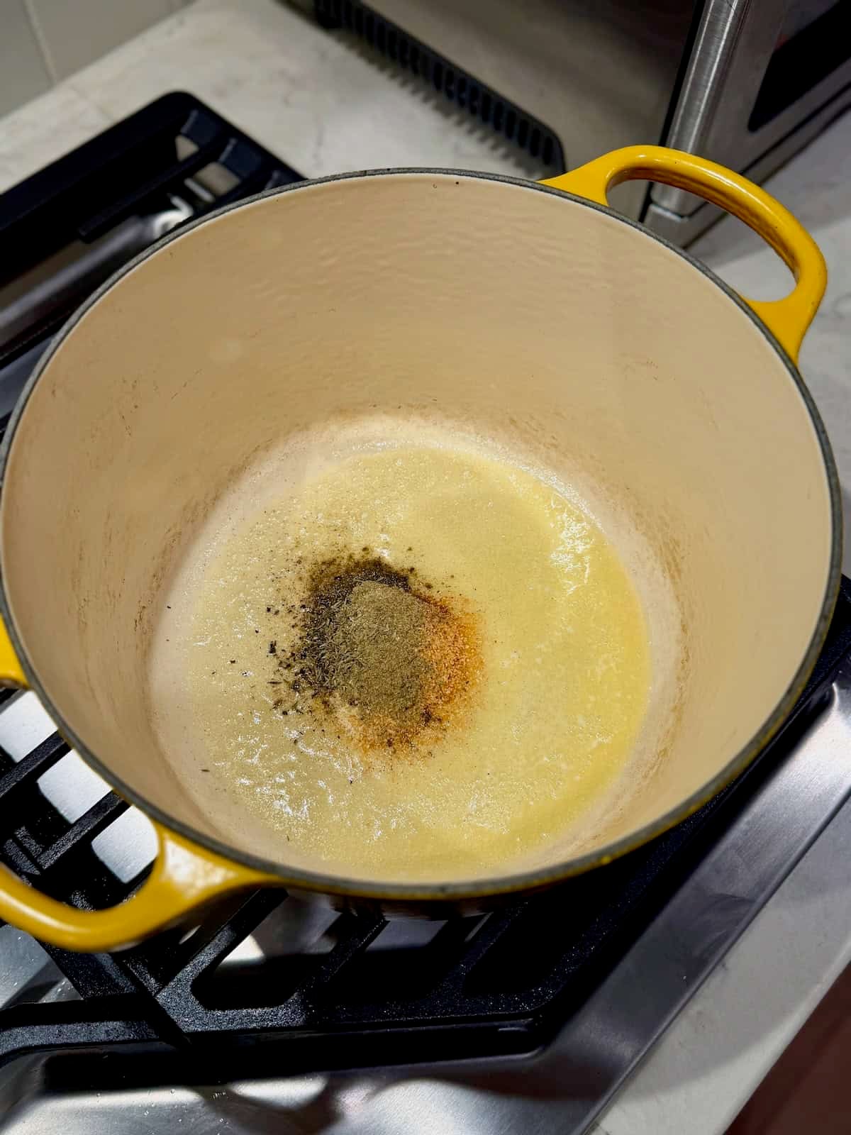 Dried seasonings are added to melted butter in a large yellow pot.