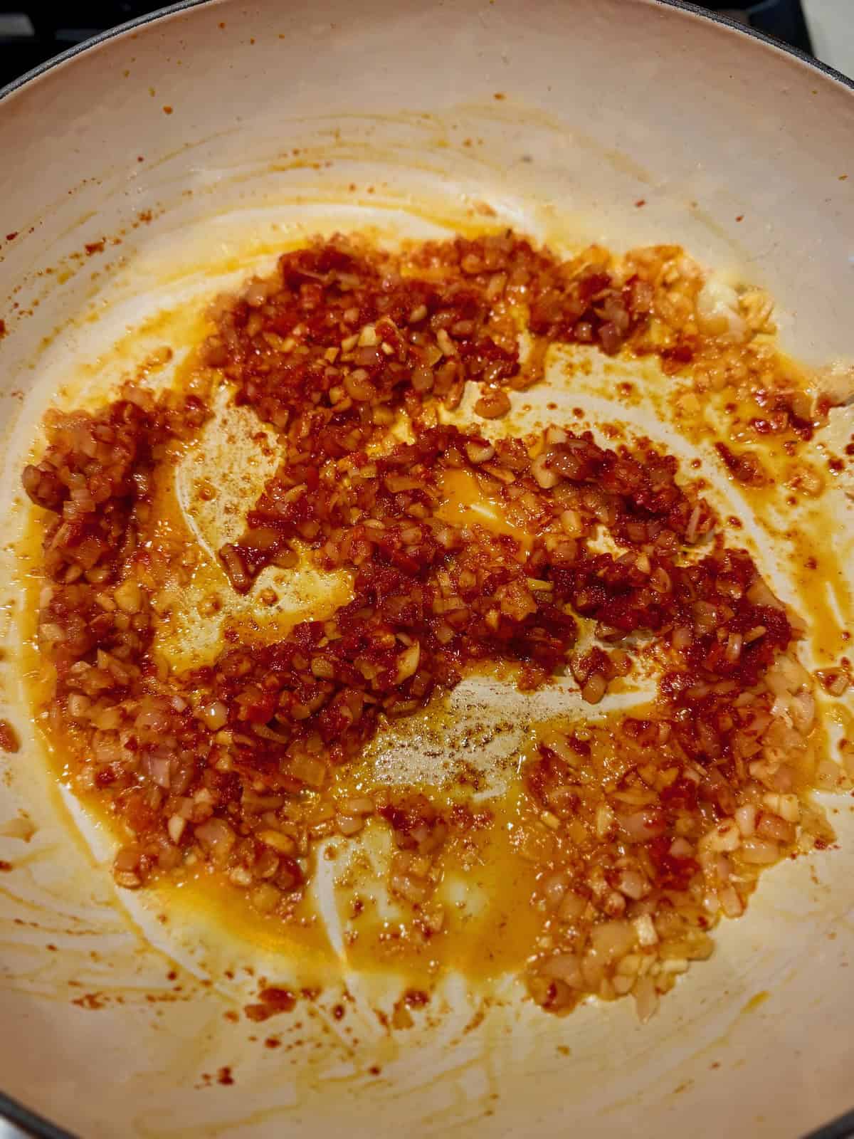 Calabrian chili paste and tomato paste cooking with shallots and garlic.