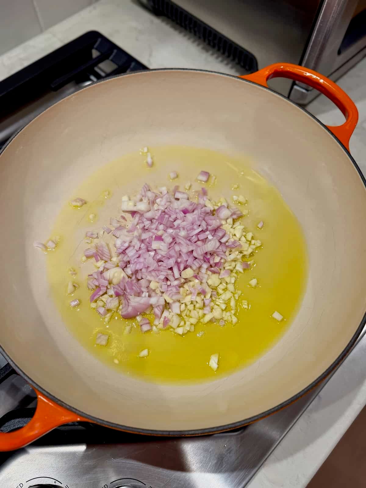 Diced shallots and garlic sautéing in olive oil for spicy Calabrian chili pasta.