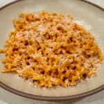 Bowl of spicy Calabrian chili pasta topped with freshly grated Parmesan cheese.