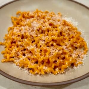 Bowl of spicy Calabrian chili pasta topped with freshly grated Parmesan cheese.