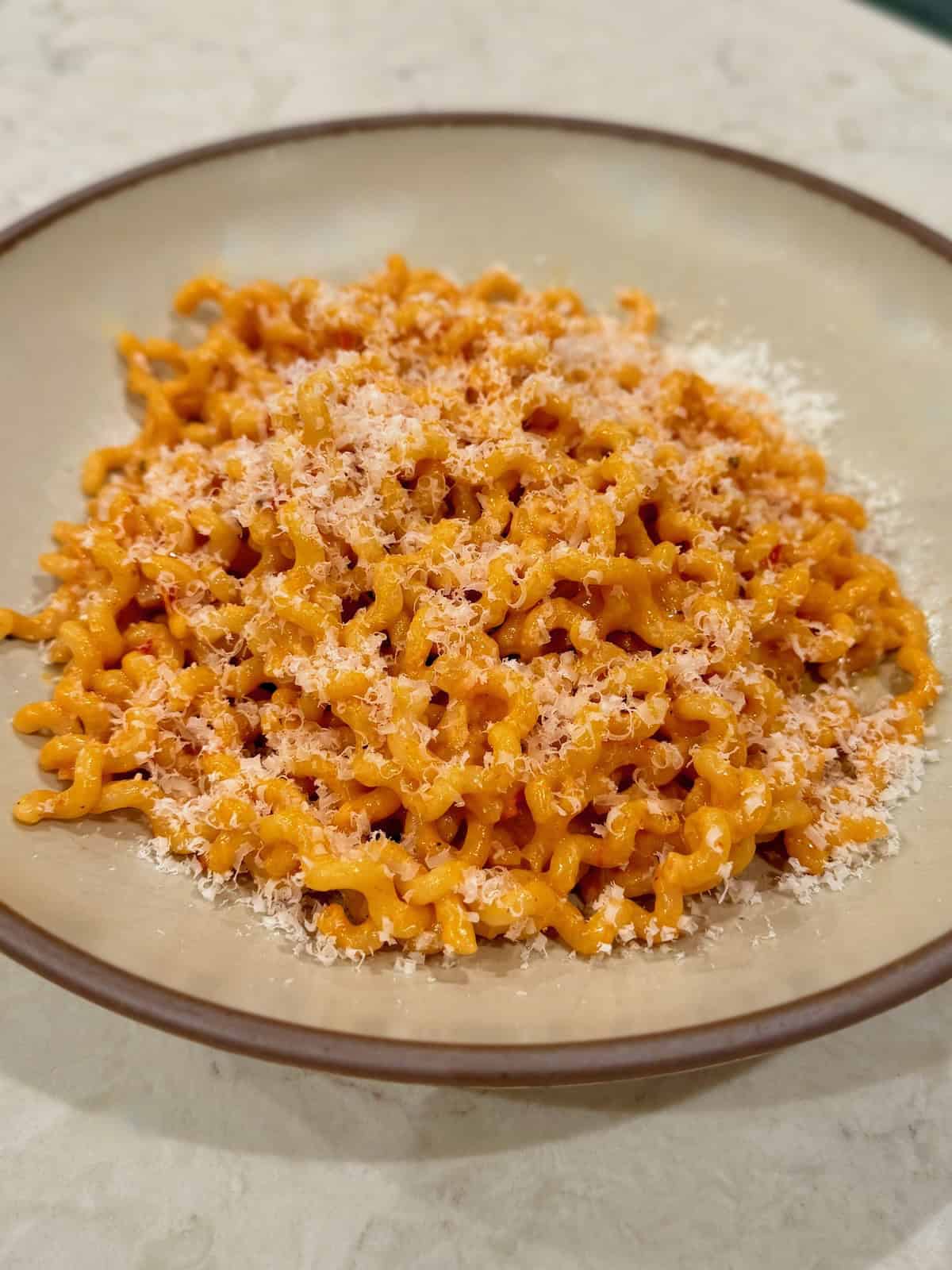 Bowl of spicy Calabrian chili pasta topped with freshly grated Parmesan cheese.
