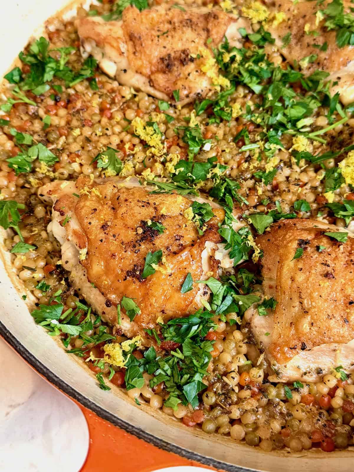 One pan crispy chicken thighs with pearl couscous, parsley, and lemon zest.