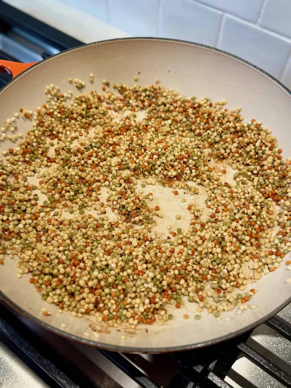 Pearl couscous toasting in large braiser.