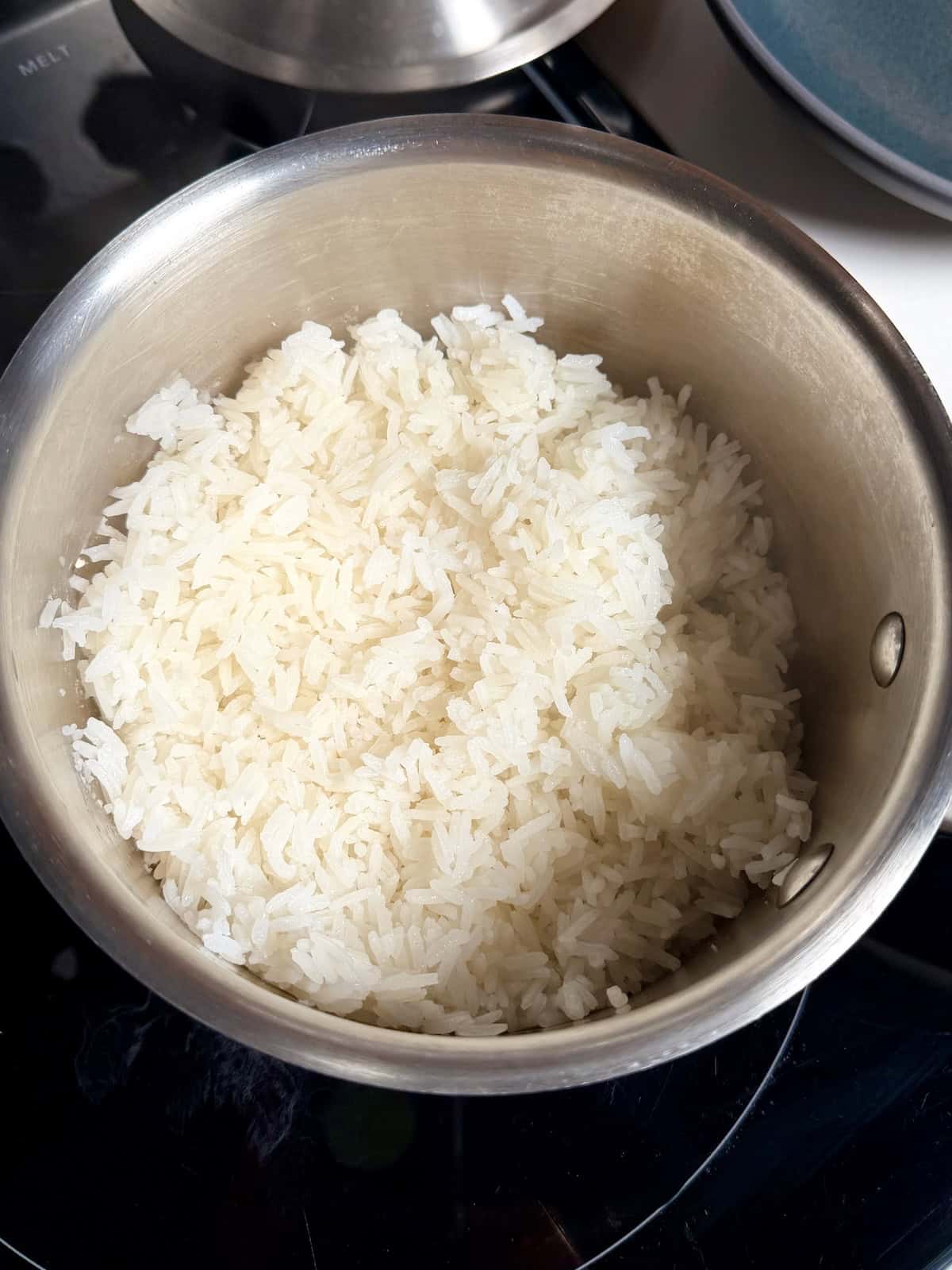 A pot of freshly cooked white rice, fluffed and ready to be served in a bowl.