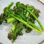 Air fried baby broccoli is served in a bowl with browned, crispy edges.