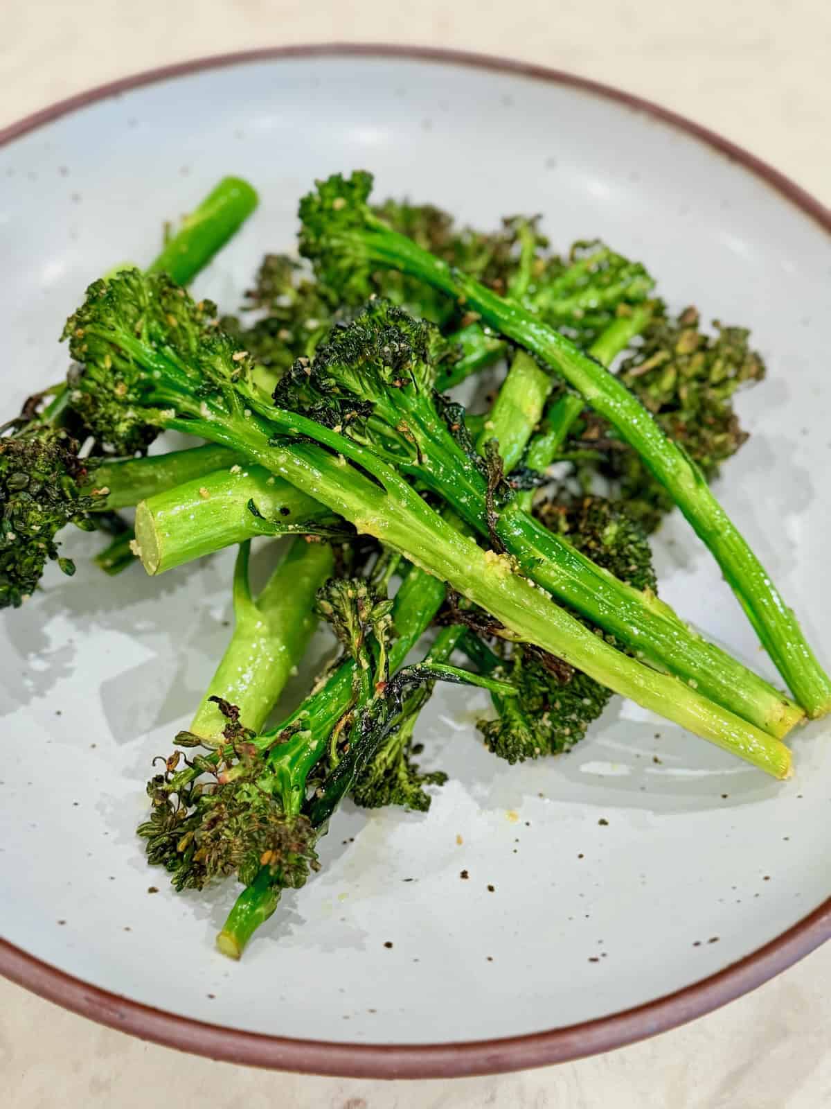 Air fried baby broccoli is served in a bowl with browned, crispy edges.