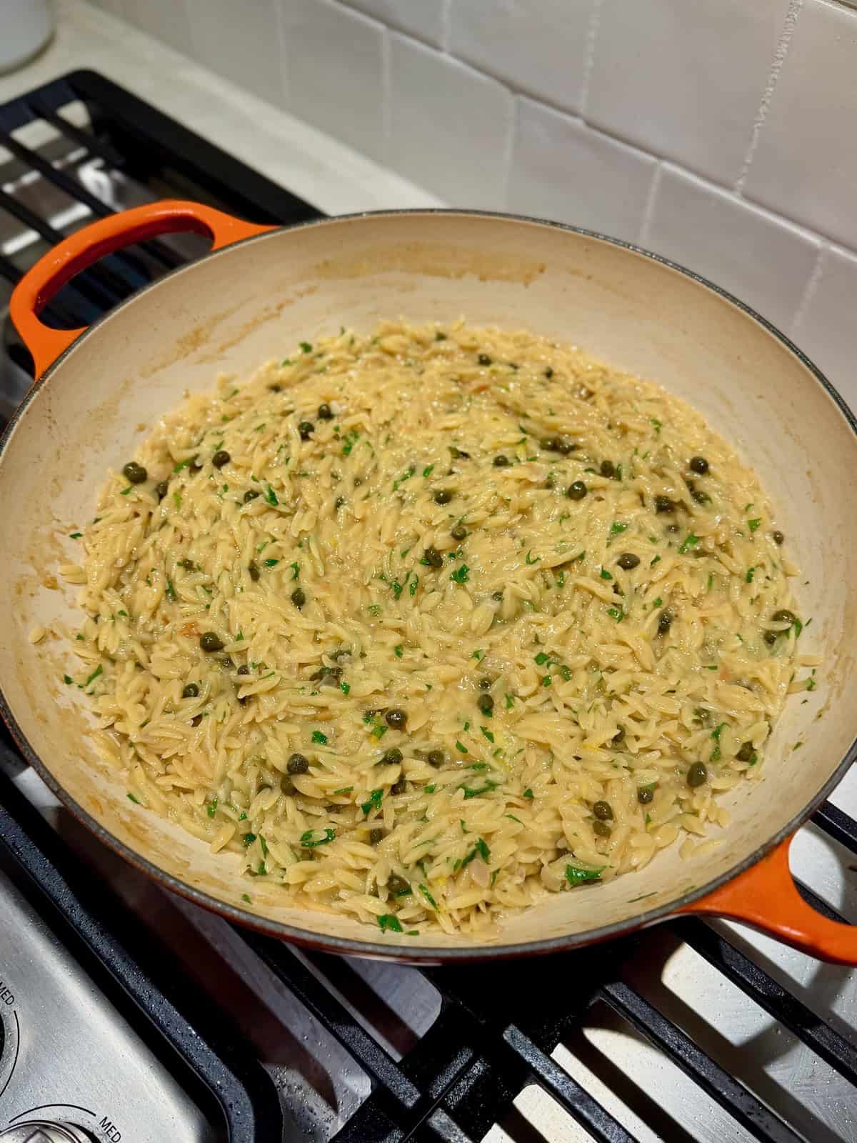 The chicken piccata orzo ingredients are mixed together in the pan before serving.