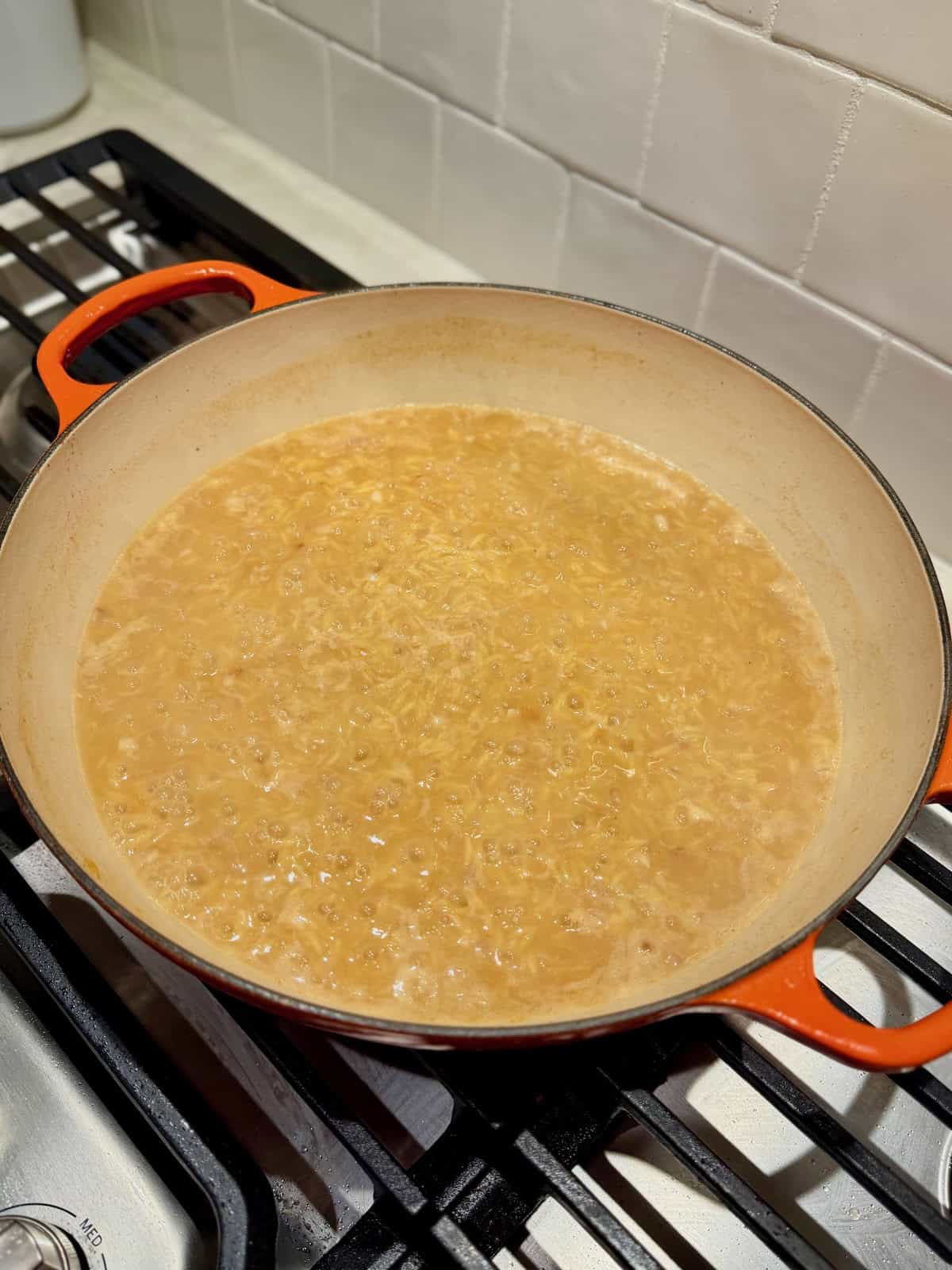 Orzo simmers in chicken broth until tender with most of the liquid absorbed.