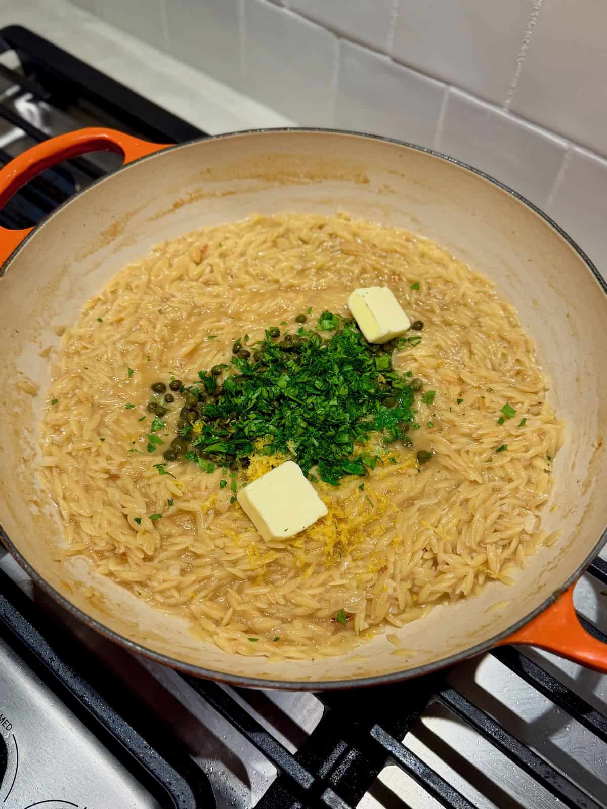 Lemon zest, capers, chopped parsley, and butter are added to the cooked orzo.