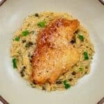 Golden chicken piccata is served over creamy lemon caper orzo with fresh parsley.