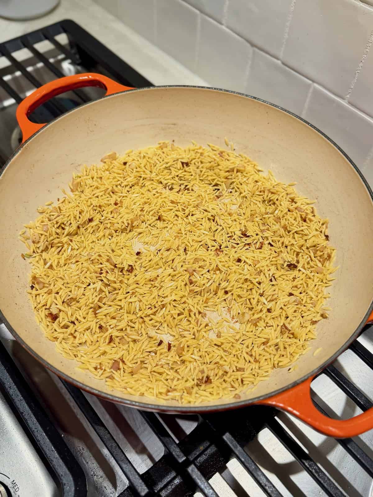 Dry orzo toasts with shallot and garlic in the same skillet.