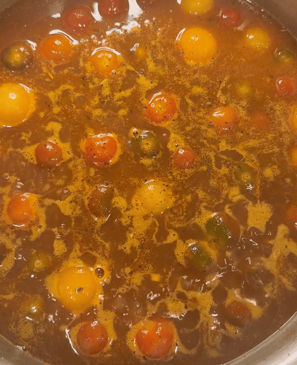 Cherry tomatoes simmering in broth.