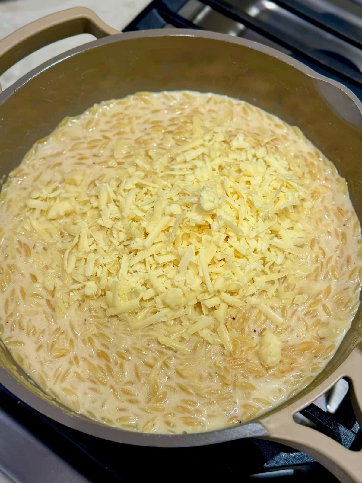 Freshly grated cheese piled over the creamy cooked orzo before stirring.