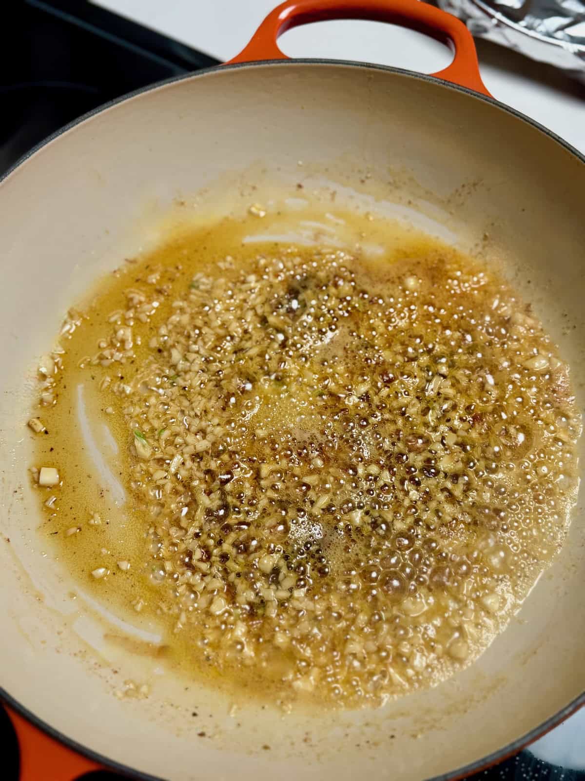 Minced garlic cooking in butter in a skillet.