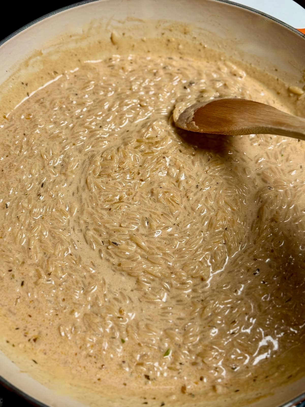 Cajun chicken alfredo orzo stirred in a pan.