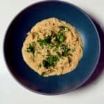 Creamy Cajun chicken Alfredo orzo garnished with fresh parsley in a blue bowl.