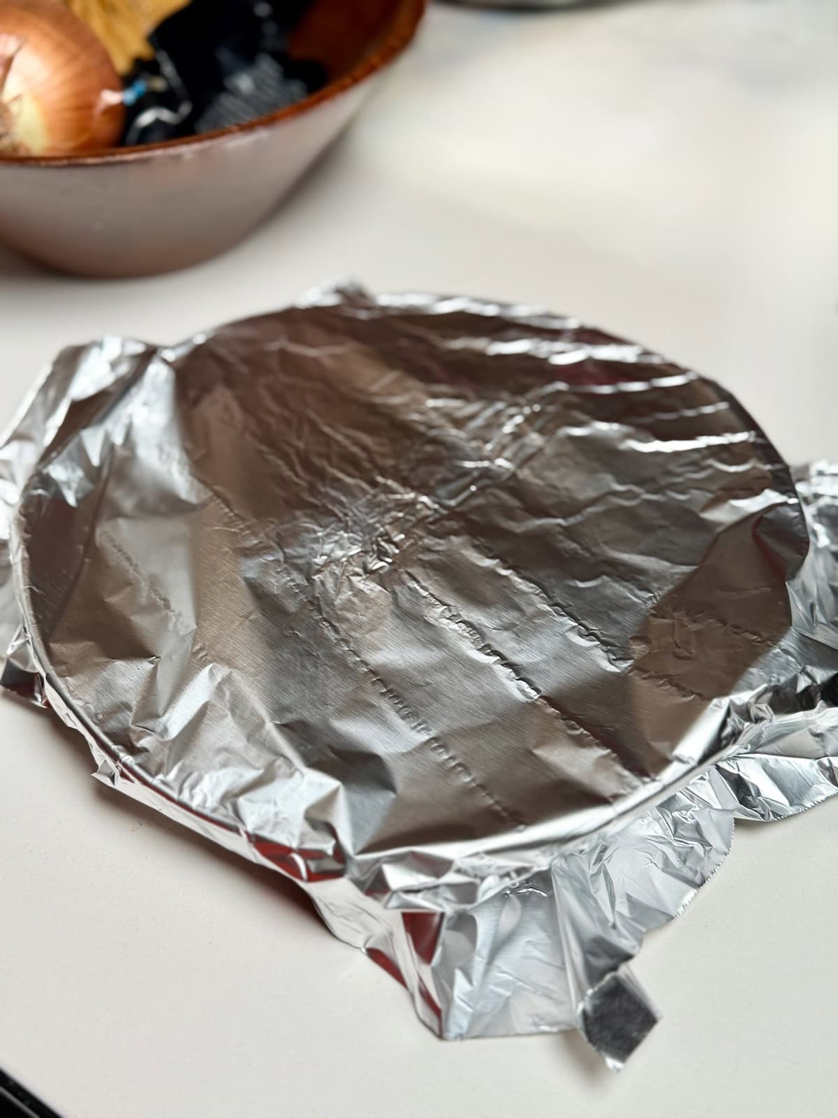 Cooked Cajun chicken resting under foil after searing.