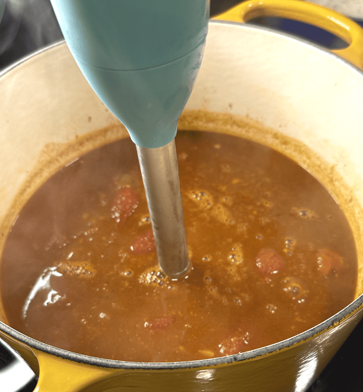 Immersion blender in broth in dutch oven.