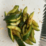 A bowl with sliced smashed cucumbers in a sauce