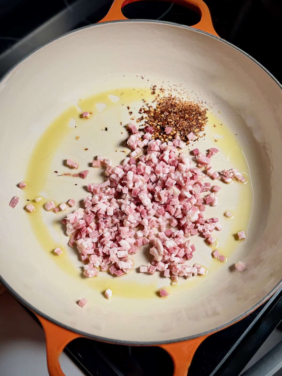 Pancetta and red pepper flakes cooking in olive oil for bucatini amatriciana.
