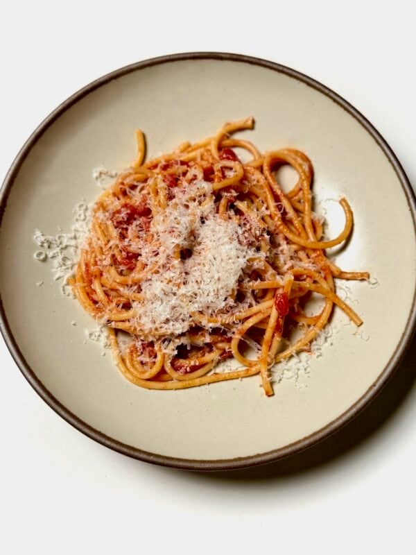 Plated bucatini amatriciana topped with grated cheese.