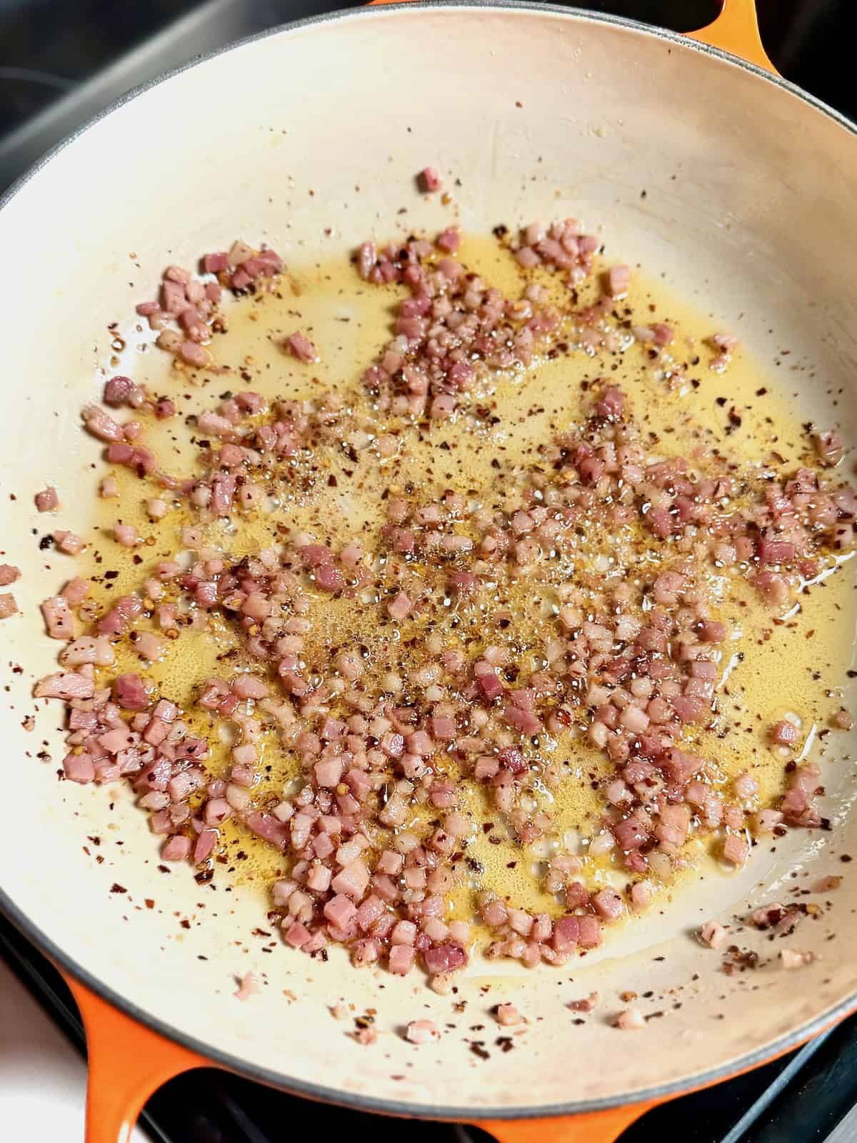 Rendered pancetta cooking in a sauté pan for bucatini amatriciana sauce.