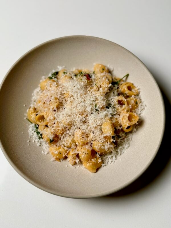 Calabrian chili spinach pasta topped with parmesan cheese in bowl for serving.