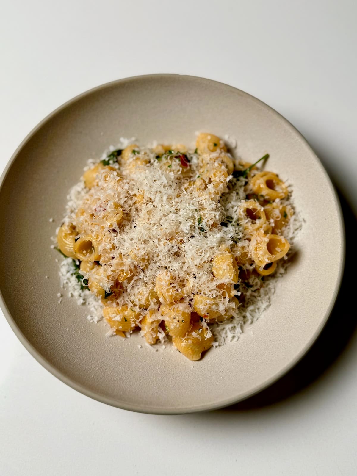 Calabrian chili spinach pasta topped with parmesan cheese in bowl for serving.
