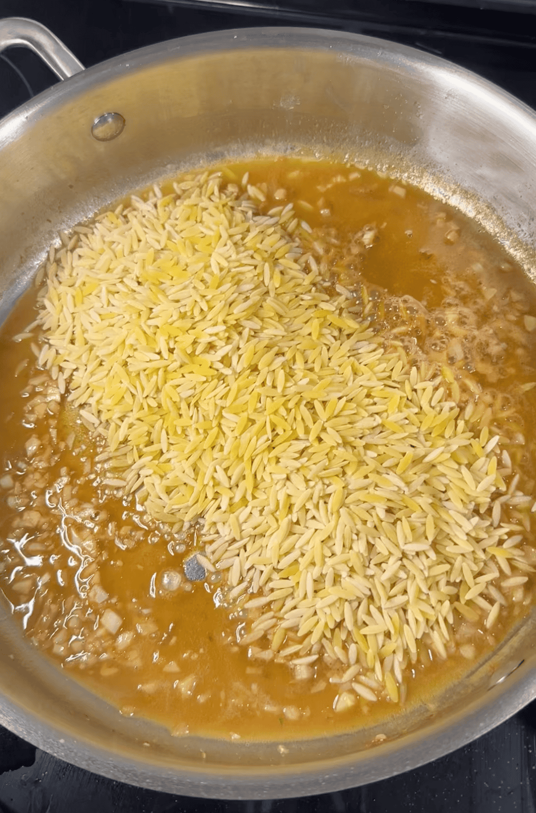 Uncooked Orzo in Pan in Broth