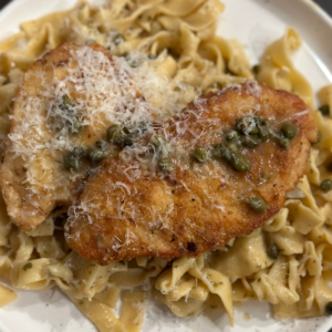 A plate with pasta, chicken, and capers