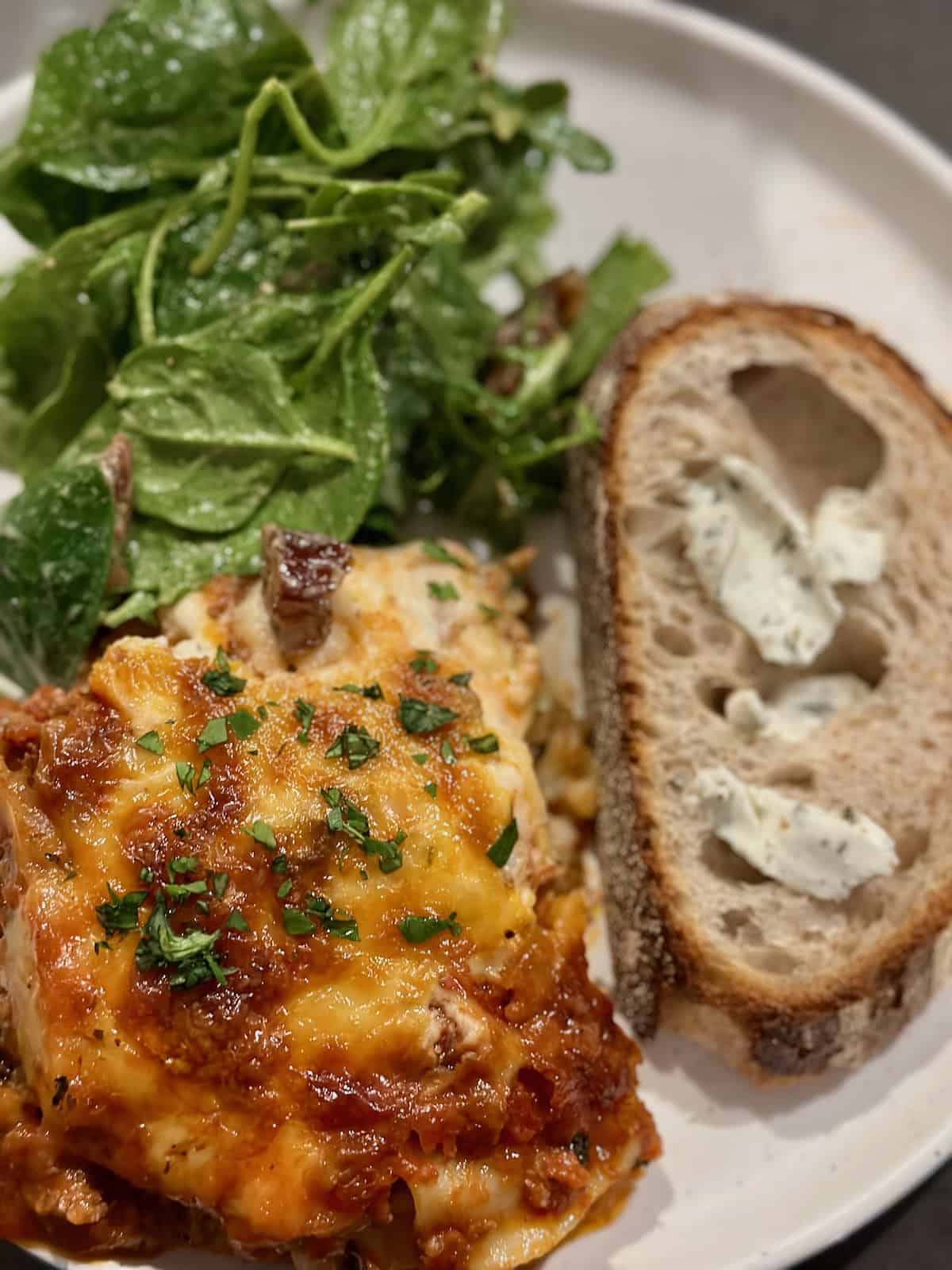 Lasagna with Bechamel on plate with bread and salad