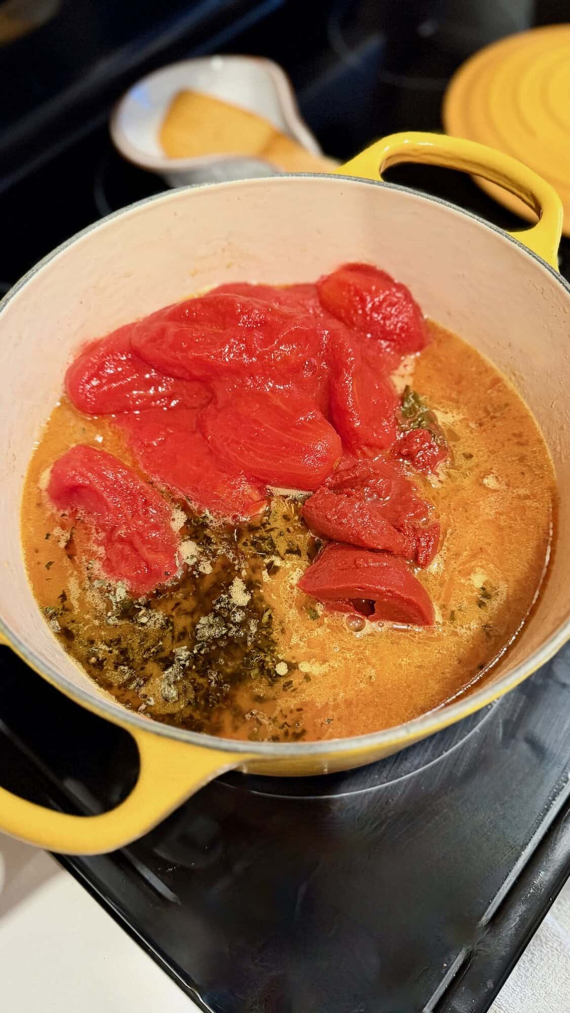 Adding tomatoes to meat sauce for lasagna.