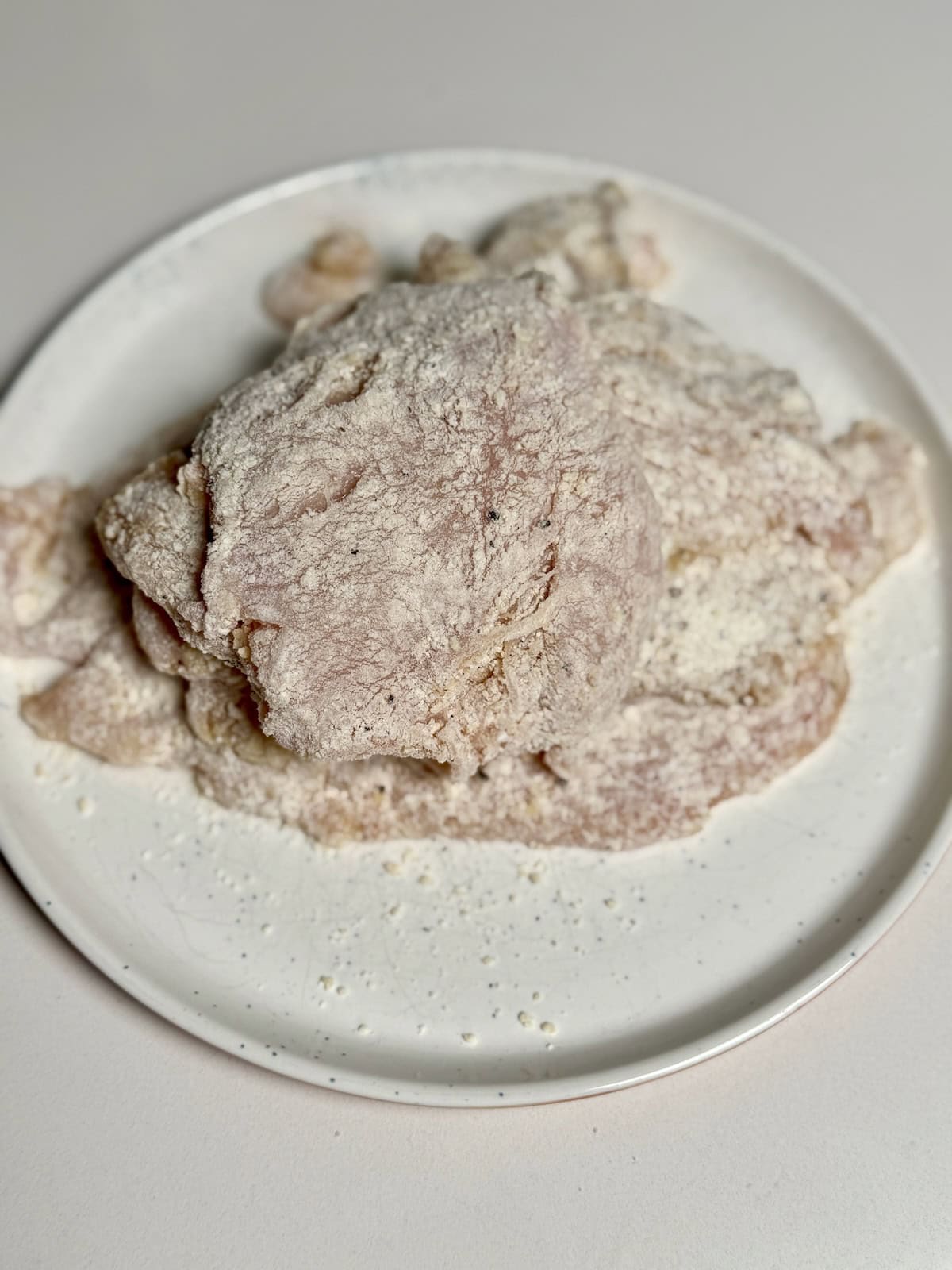 Chicken breasts coated in flour and parmesan for chicken piccata.