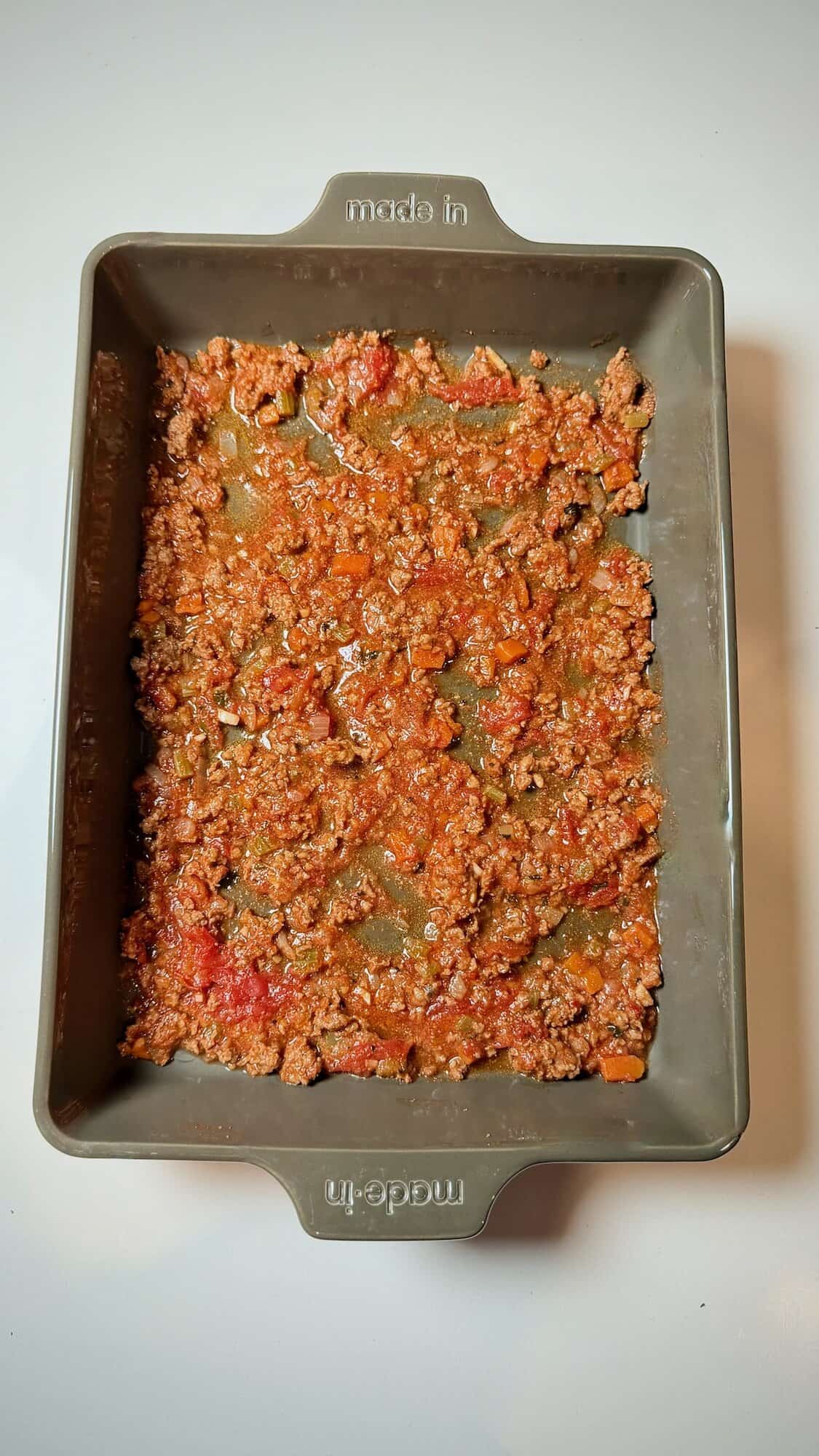 Meat sauce layer spread evenly for lasagna.