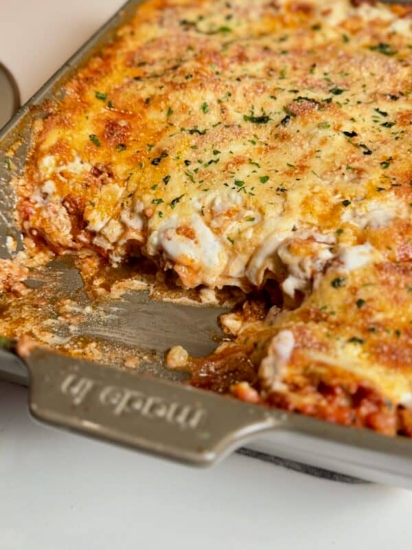 Baked lasagna with béchamel showing removed slice in pan.