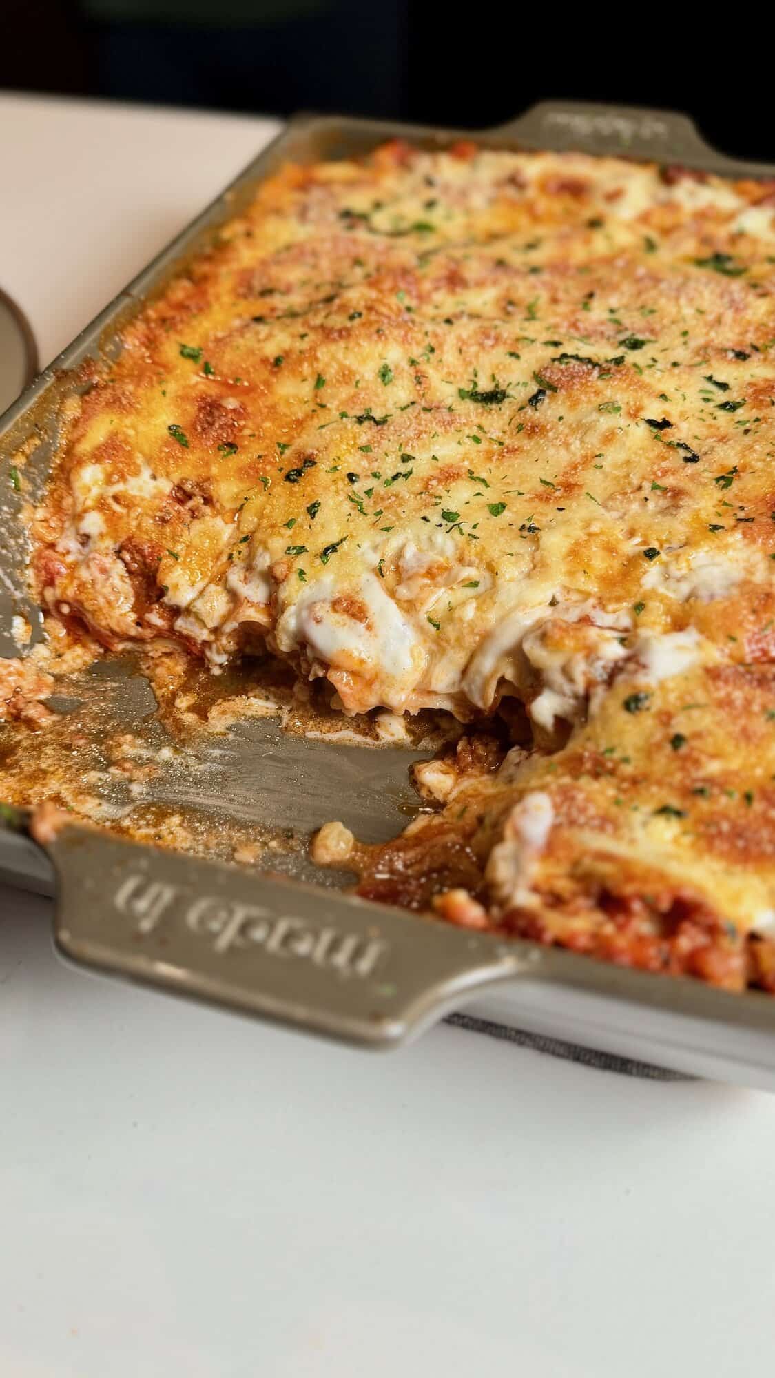 Baked lasagna with béchamel showing removed slice in pan.