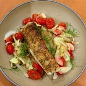 Crispy Chilean sea bass is served over roasted fennel, tomatoes, and onion.