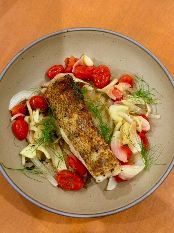 Crispy Chilean sea bass is served over roasted fennel, tomatoes, and onion.