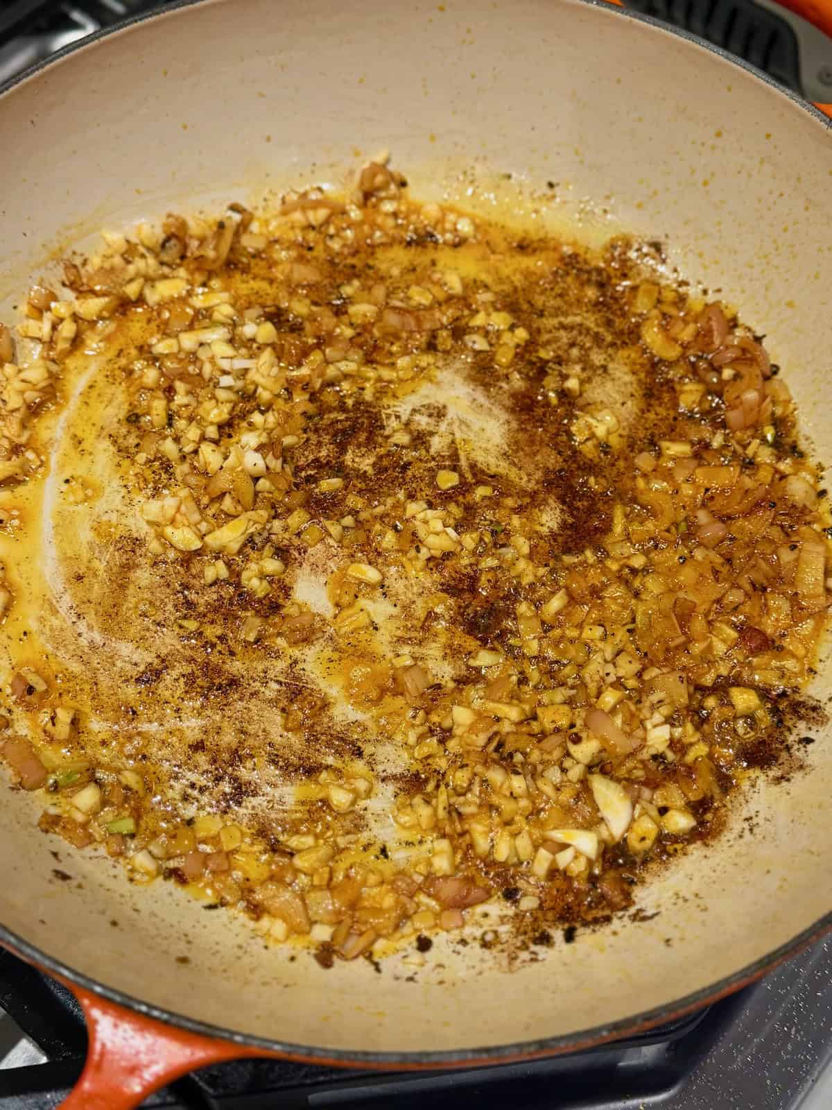 Chopped shallot and garlic cook in the seasoned chicken drippings.