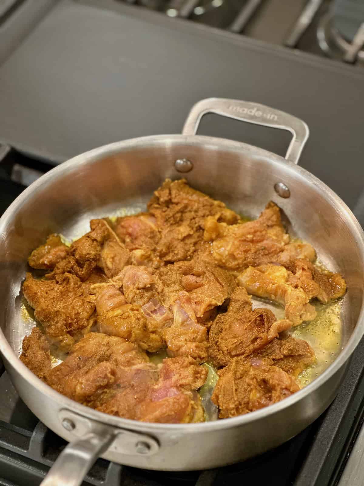 Seasoned chicken thighs cooked in a skillet for chicken shawarma orzo.