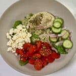 Bowl with couscous, pesto hummus, cucumbers, tomatoes, and feta