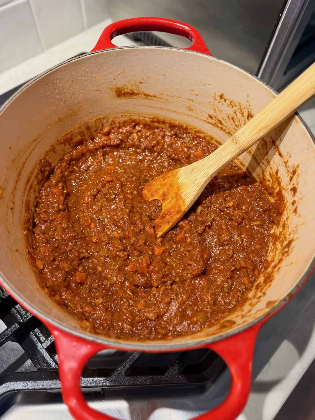 Thick Chinese-Italian beef Ragu fills a red Dutch oven after simmering.