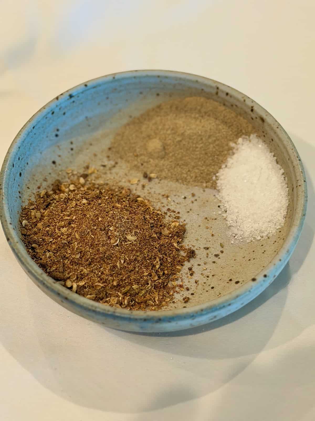 Freshly toasted spices ground, white pepper, and salt in a small bowl.