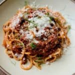 Spaghetti with Chinese-Italian Ragu is topped with Parmesan and fennel fronds.