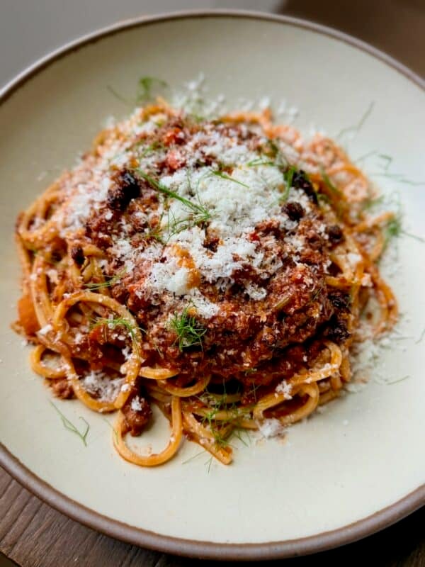 Spaghetti with Chinese-Italian Ragu is topped with Parmesan and fennel fronds.
