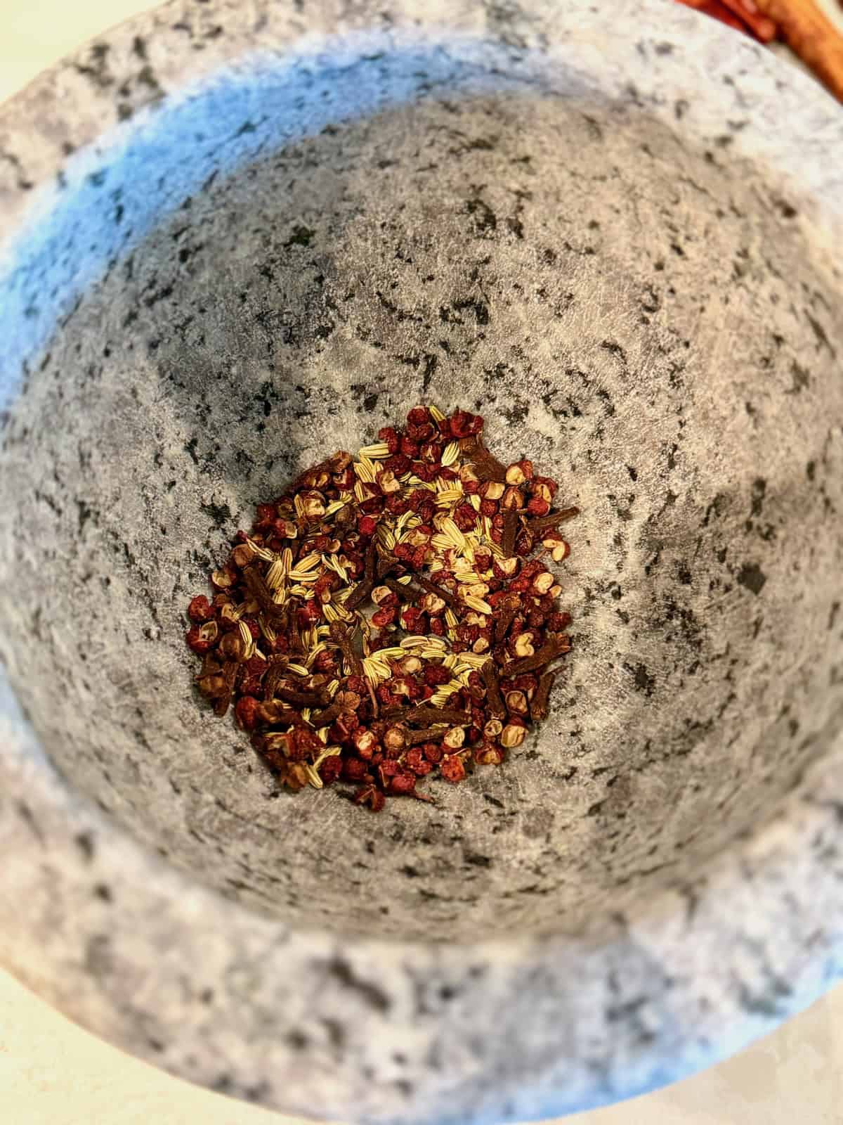 Toasted whole spices in a mortar before grinding.