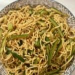 A bowl with noodles, cucumbers, with a spicy sauce
