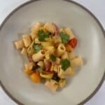 A white bowl with rigatoni pasta and roasted vegetables